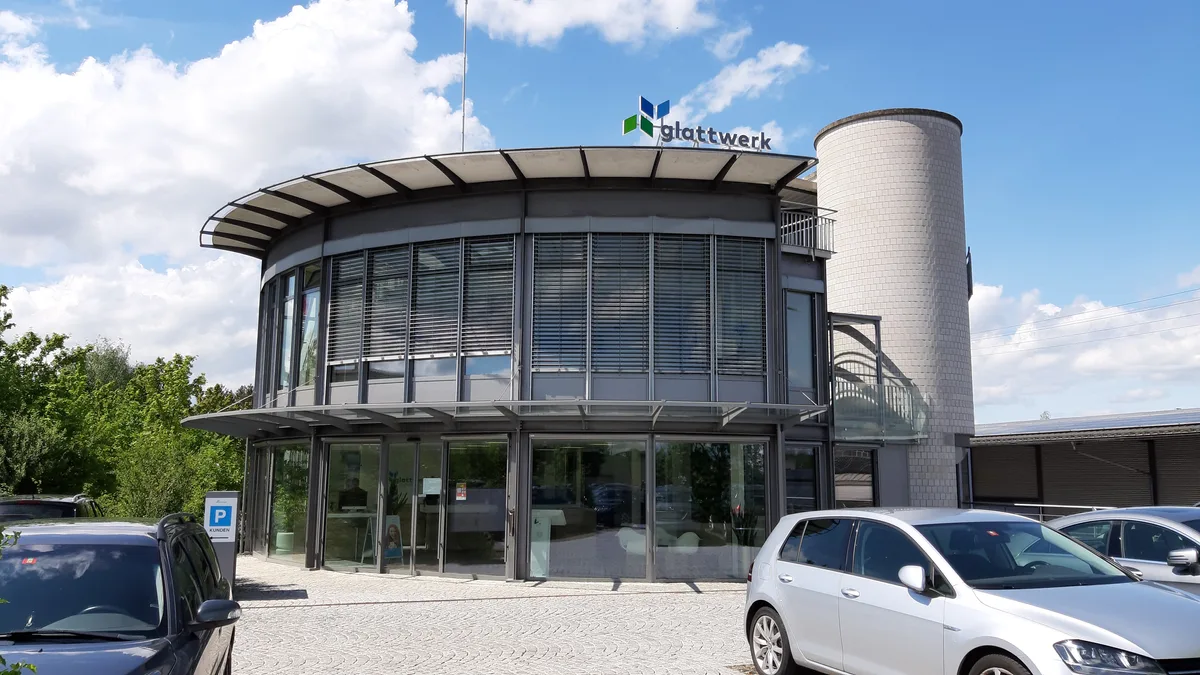 Blick auf ein zweistöckiges Gebäude mit runder Fensterfront. 